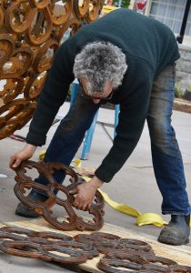 Sculptor Vaughn Randall assembles individual castings into the spherical sculpture, spanning 8 feet in diameter, at Downtown Commons.